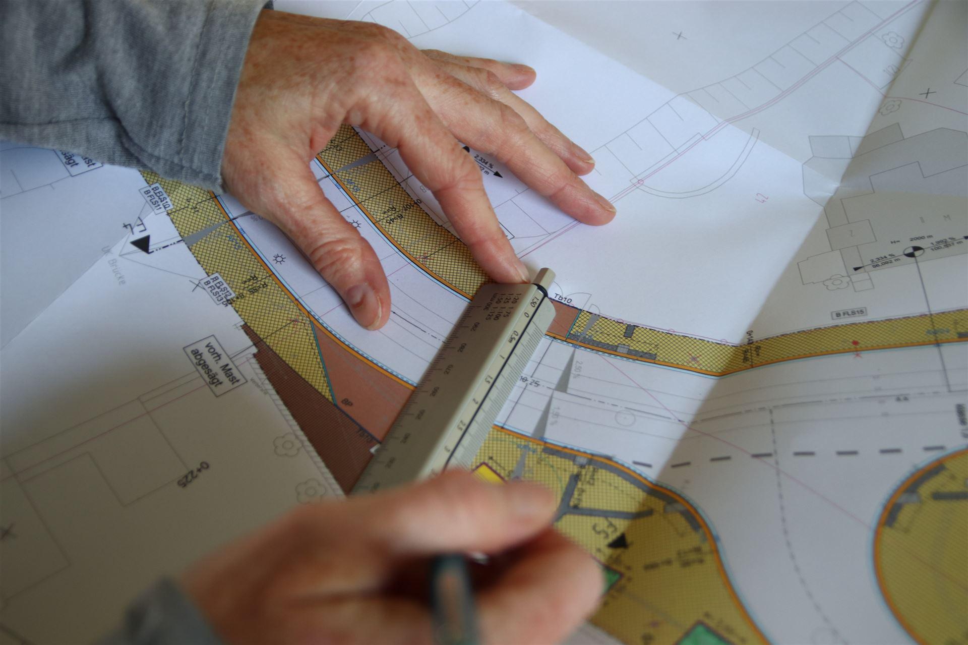 Hand hält Maßstab auf Plan